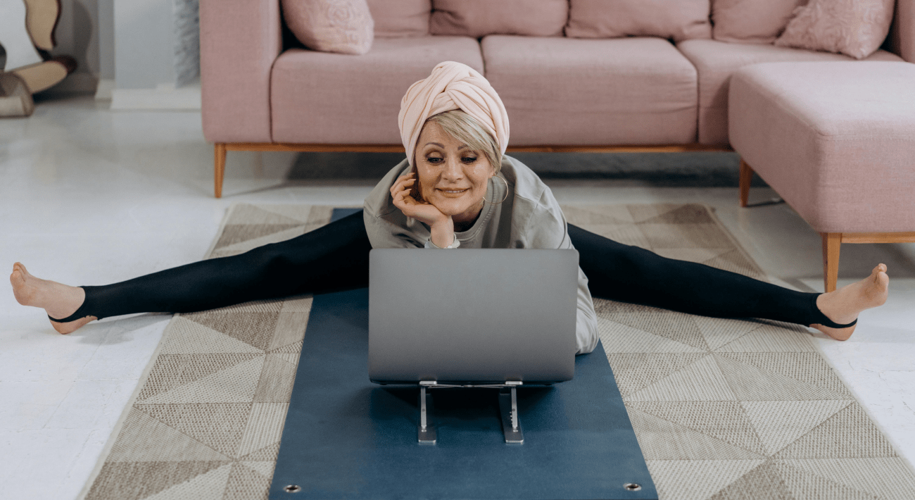 Come stare bene a casa con il Feng Shui. Una signora sorridente fa stretching mentre lavora al pc