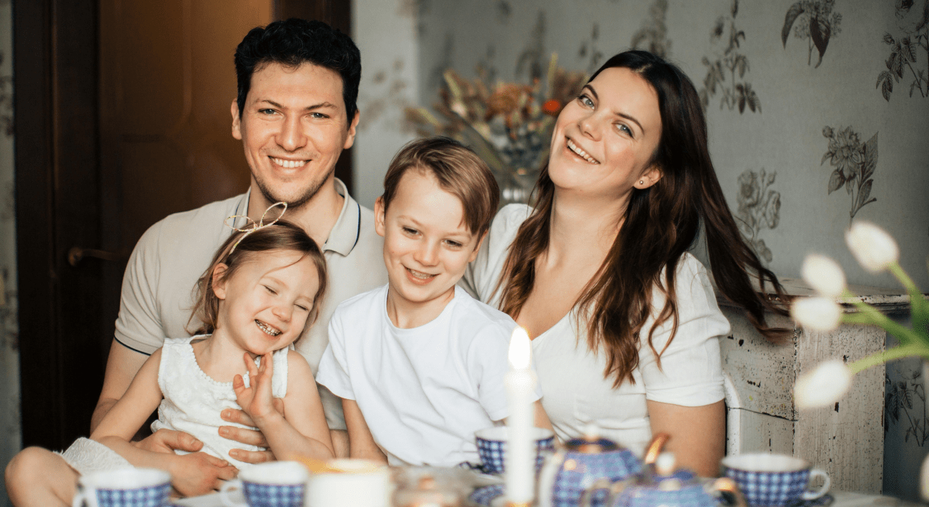 Casa e Famiglia. Marito e moglie a tavola con i loro 2 figli, un bambino più grande e una bambina più piccola