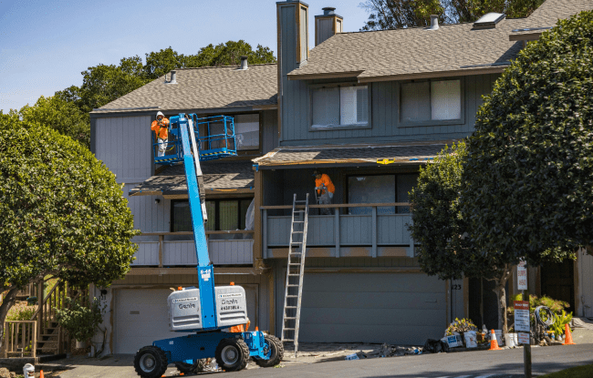 operai in divisa arancione al lavoro per ristrutturare l'esterno di una casa