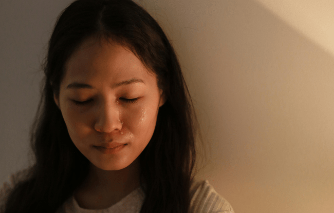 Una lacrima scivola sul volto di una donna dai capelli neri