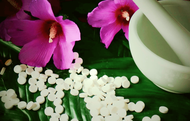 I sali di Schüssler poggiati su delle foglie verdi con affianco una ciotola in ceramica bianca