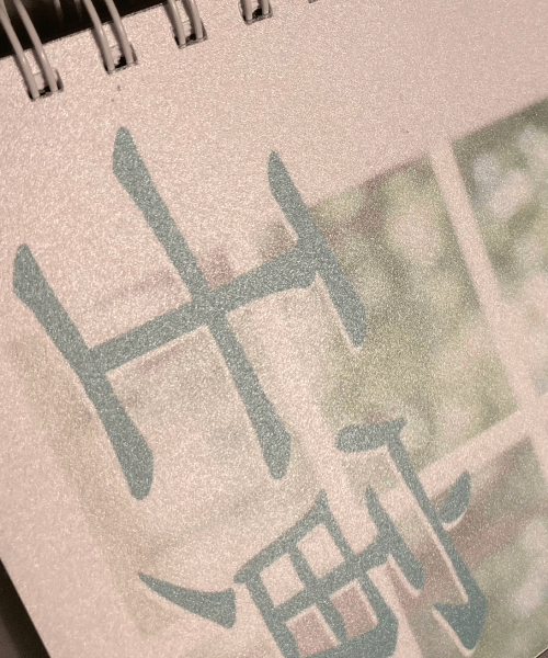 Una foto di un quaderno a spirale con un simbolo cinese su di esso.