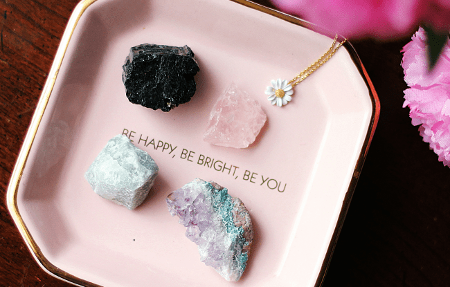 Piccoli cristalli tra cui il quarzo rosa dentro una scatoletta con la scritta "be happy, be right, be you"