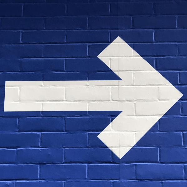 Una freccia bianca dipinta su un muro blu a rappresentare il fare la cosa giusta secondo il Ba Zi