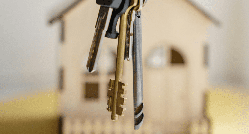 un mazzo di chiavi con uno sfondo sfocato che rappresenta una casa in miniatura. nella mia frase preferita nel Feng Shui rappresenta il fare la cosa giusta e scegliere casa consapevolmente